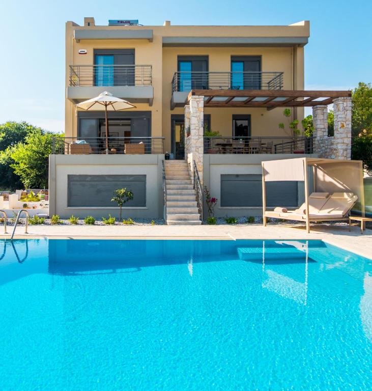 a villa with a swimming pool in front of a house at Azure Villa Kanoni in Análipsis
