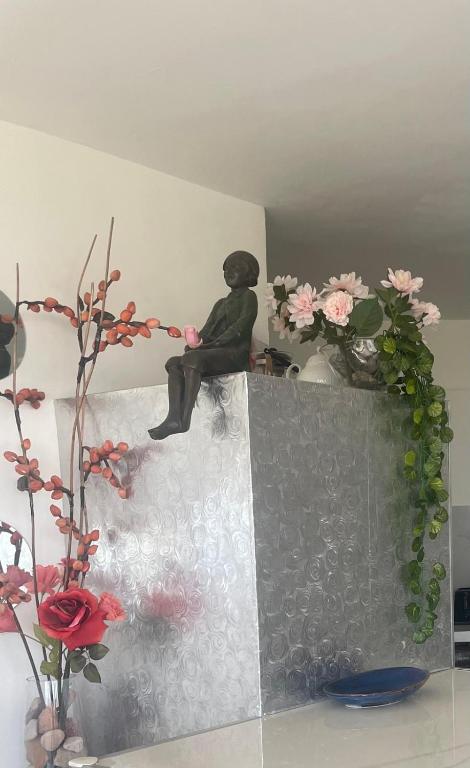 a statue of a man sitting on a ledge with flowers at 123Eilat panorama in Eilat