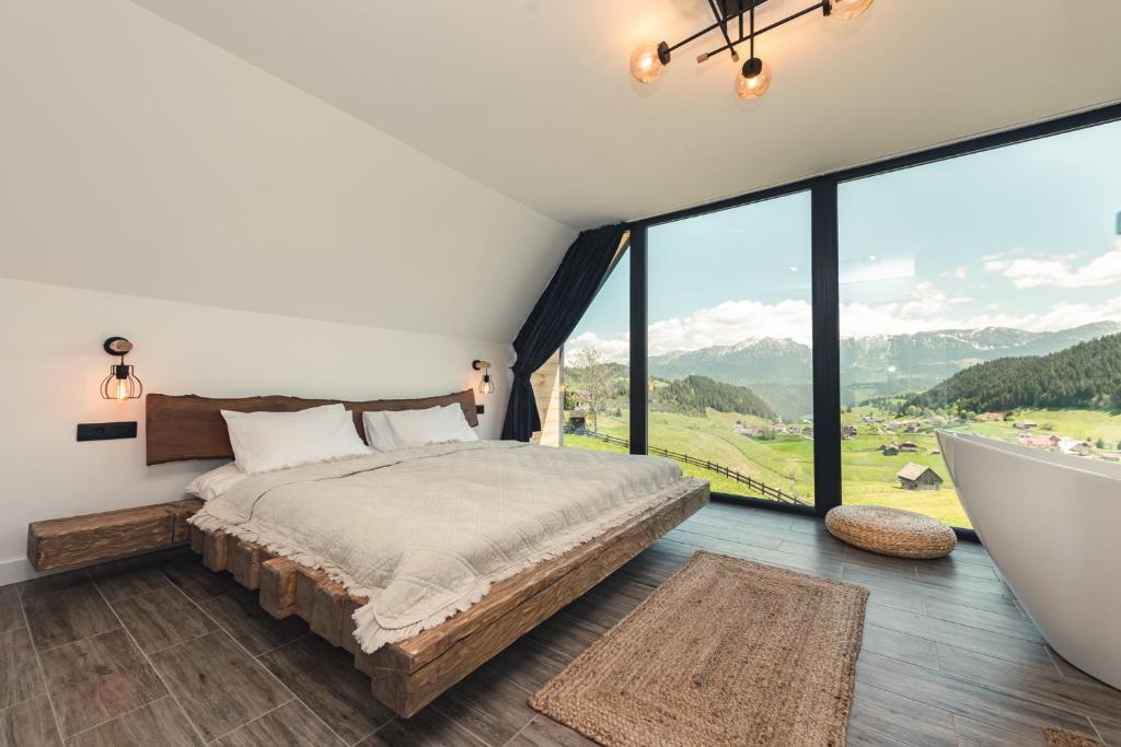 a bedroom with a bed and a large window at Serra Chalet in Fundata
