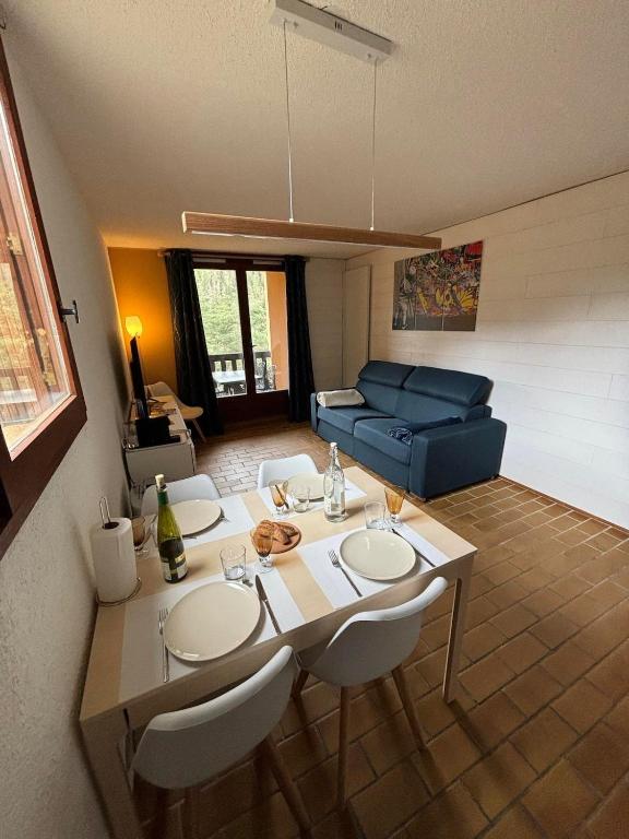 a living room with a table and a blue couch at Appartement 2 pièces La Colmiane in La Colmiane