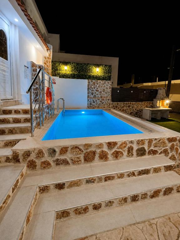 a swimming pool in the middle of a house at night at Katsaras Sunset & Pool House in Kremasti
