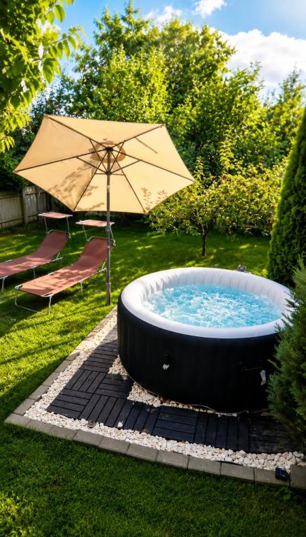 a hot tub in a yard with an umbrella at The Green House - Jacuzzi & Garden Escape in Timişoara