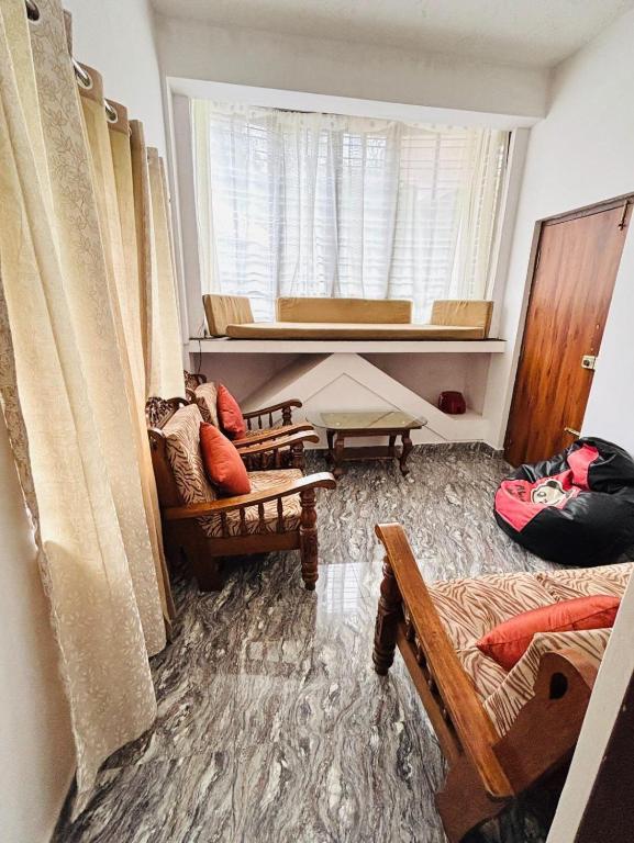 a living room filled with furniture and a window at Sai Srushti Homes in Gonikoppal
