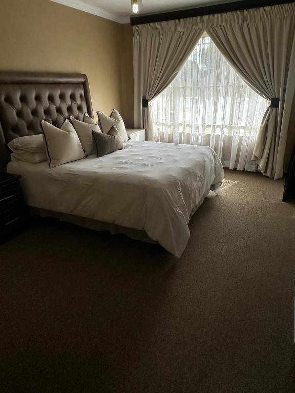 a bedroom with a large bed with a large window at Diamo Guest House in Roodeplaat