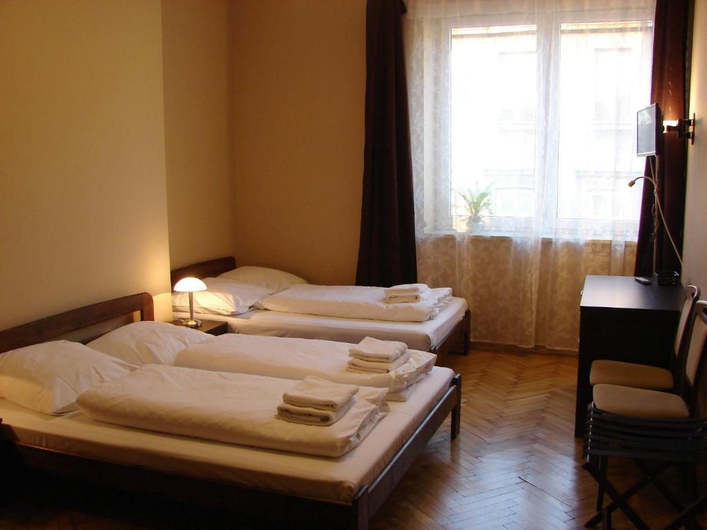 3 camas en una habitación con ventana en Krovo Apartments en Cracovia
