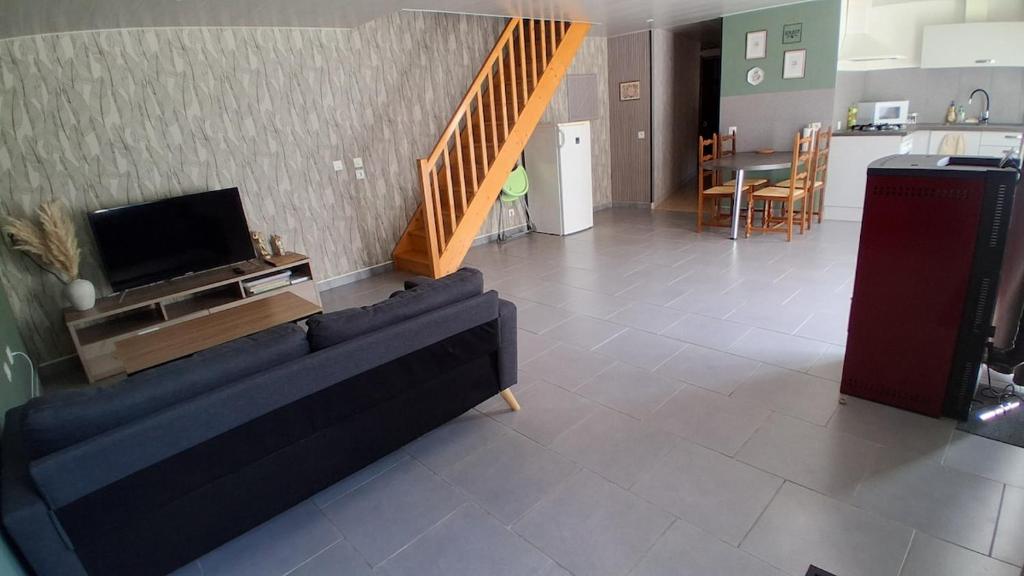 a living room with a couch and a tv and a kitchen at Chez Nova in Chaudenay