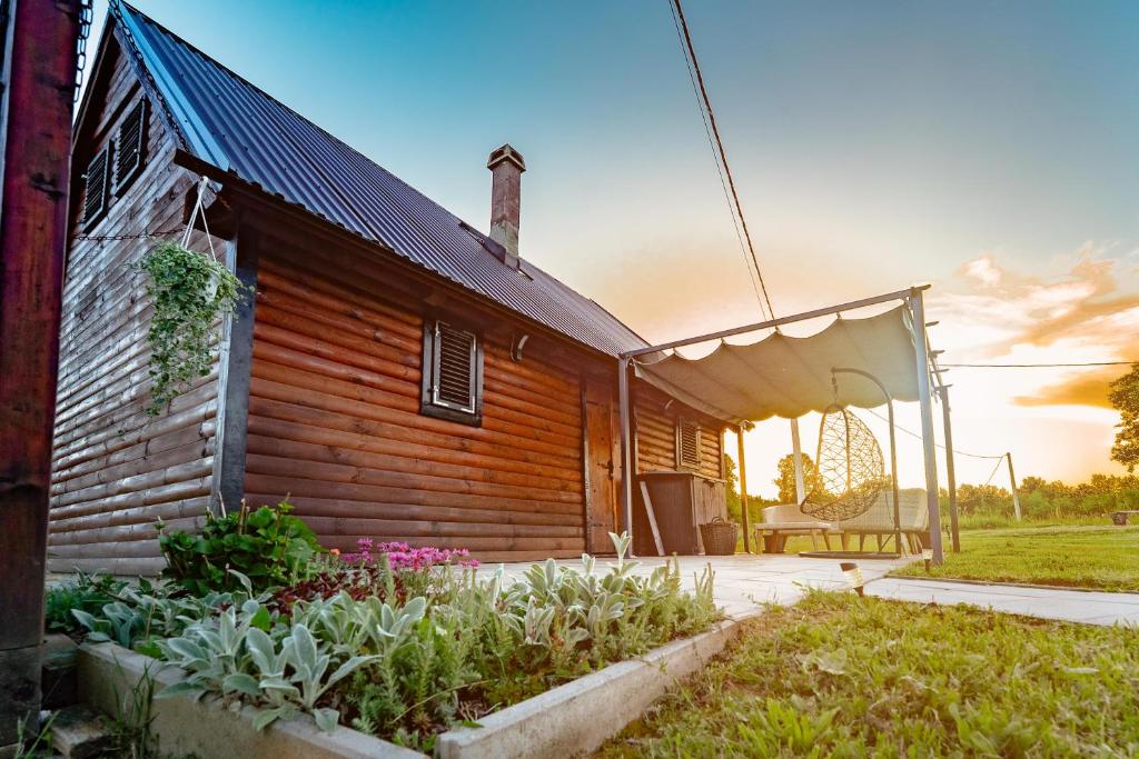 a wooden house with a garden in front of it at Dedekov gaj in Oteš