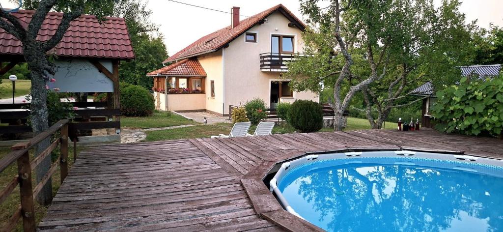 a swimming pool on a wooden deck in front of a house at Guesthouse Mirko Hodak in Seliste Dreznicko