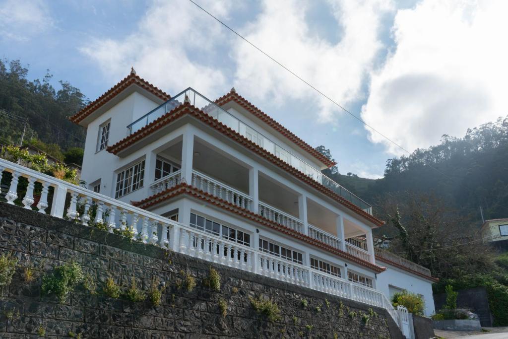 a white house on top of a stone wall at Casa Borboleta in Arco da Calheta