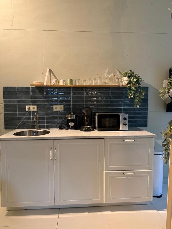 a kitchen counter with a sink and a microwave at Zen appartement in Vries