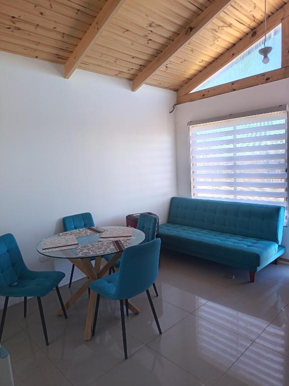a living room with a couch and a table and chairs at Cabaña Litueche in Los Manantiales