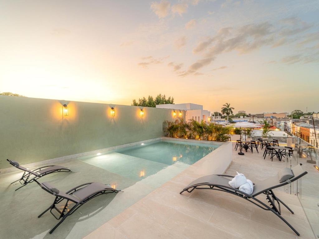 a swimming pool with two lounge chairs and a pool at New Hotel Serenata Santa Lucia Mérida in Mérida