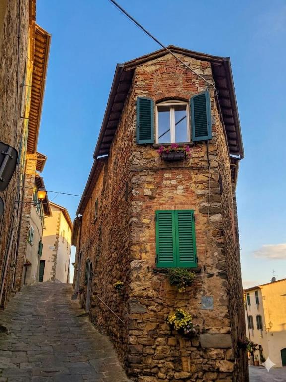 a stone building with green shutters and a window at L'Angolo dei Sogni in Lucignano