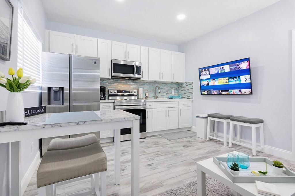a kitchen with white cabinets and a stainless steel refrigerator at Mayas Blue Lagoon Luxury Suite #2 in Fort Lauderdale