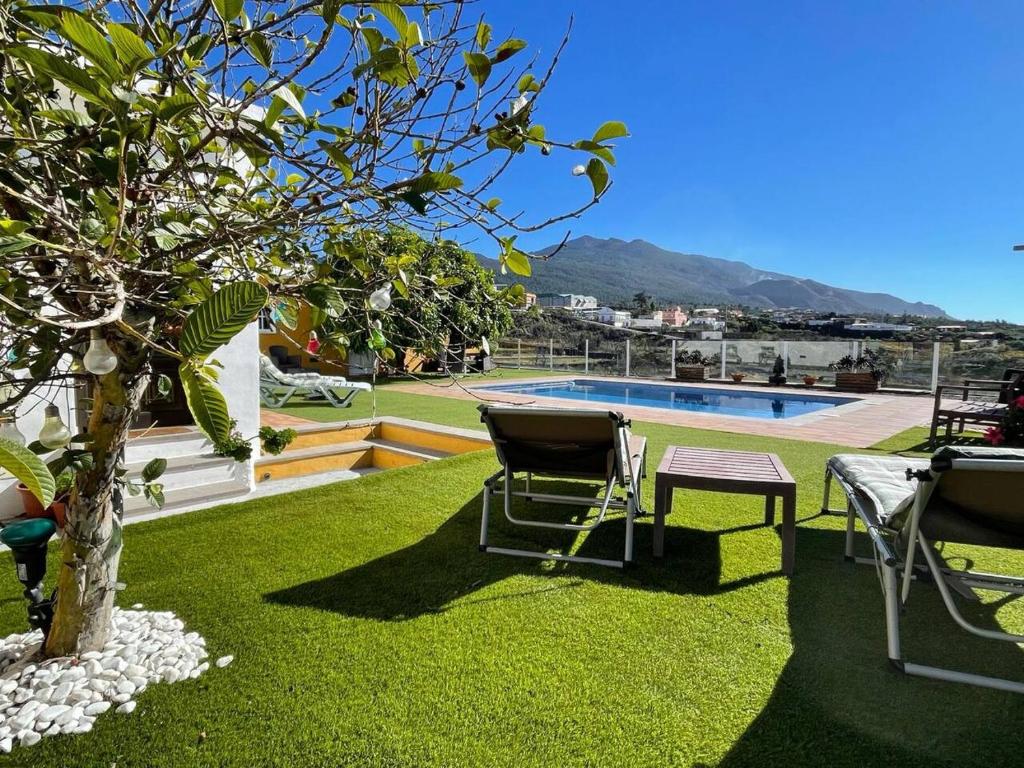 a yard with chairs and a swimming pool at El Mirador de El Paso - vistas y piscina in El Paso