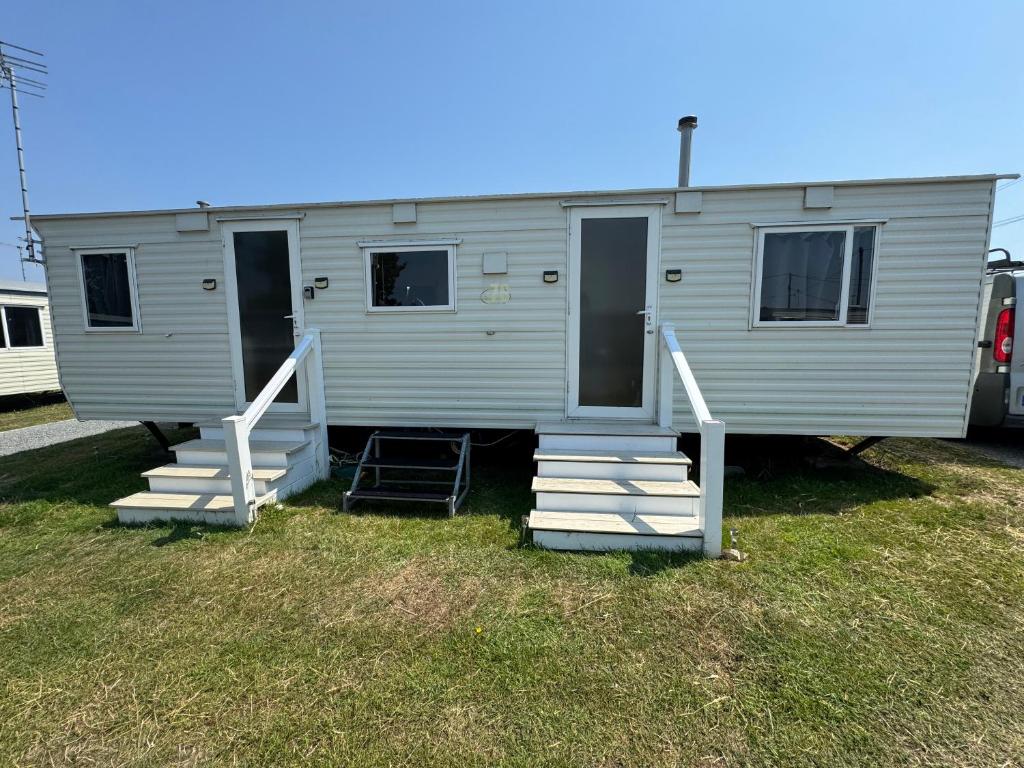 a gray mobile home with stairs and a porch at Sweet Caravan - Hemsby in Hemsby