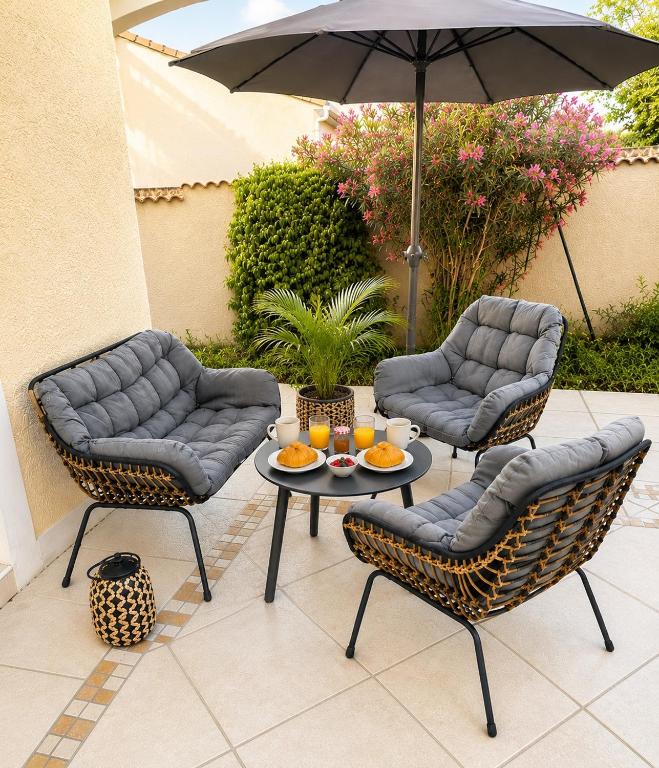 a patio with two chairs and a table and an umbrella at Studio climatisé SPA en option in Jacou