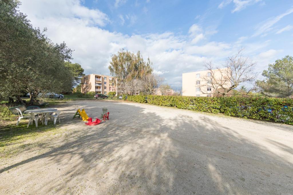 a dirt road with tables and chairs in a park at Appartement Les Elfes in Le Pradet