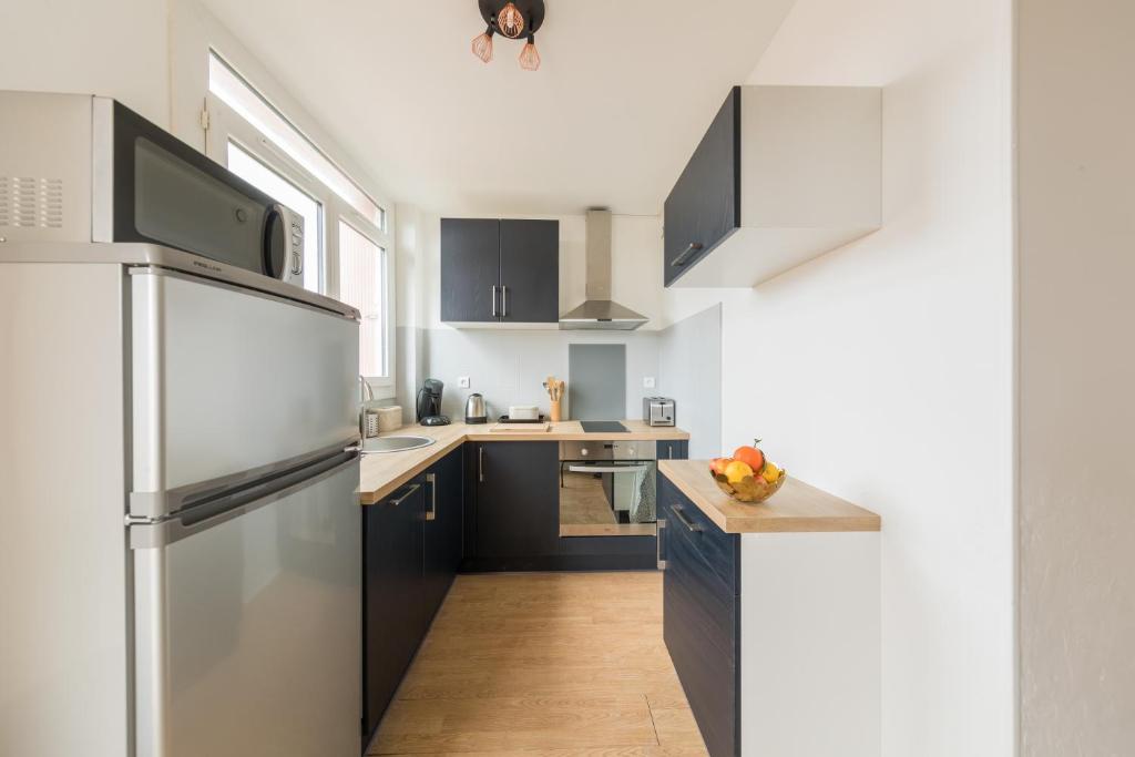 a kitchen with black cabinets and a stainless steel refrigerator at Appartement Les Elfes in Le Pradet