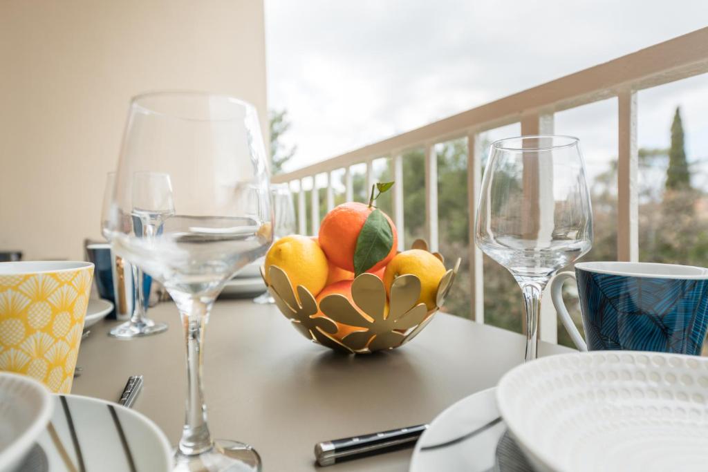 a table with two wine glasses and a bowl of fruit at Appartement Les Elfes in Le Pradet