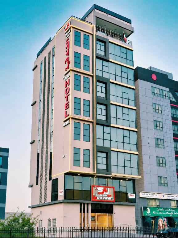 a tall building with a red sign on it at The Saj Hotel Apartments in Ras al Khaimah