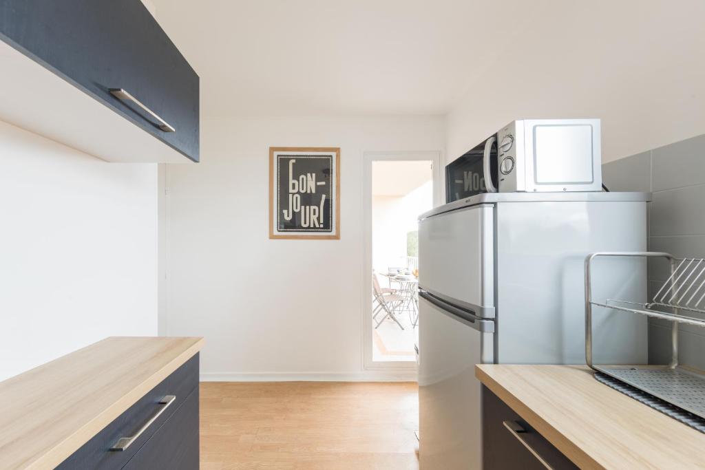 a kitchen with a refrigerator and a microwave at Appartement Les Elfes in Le Pradet
