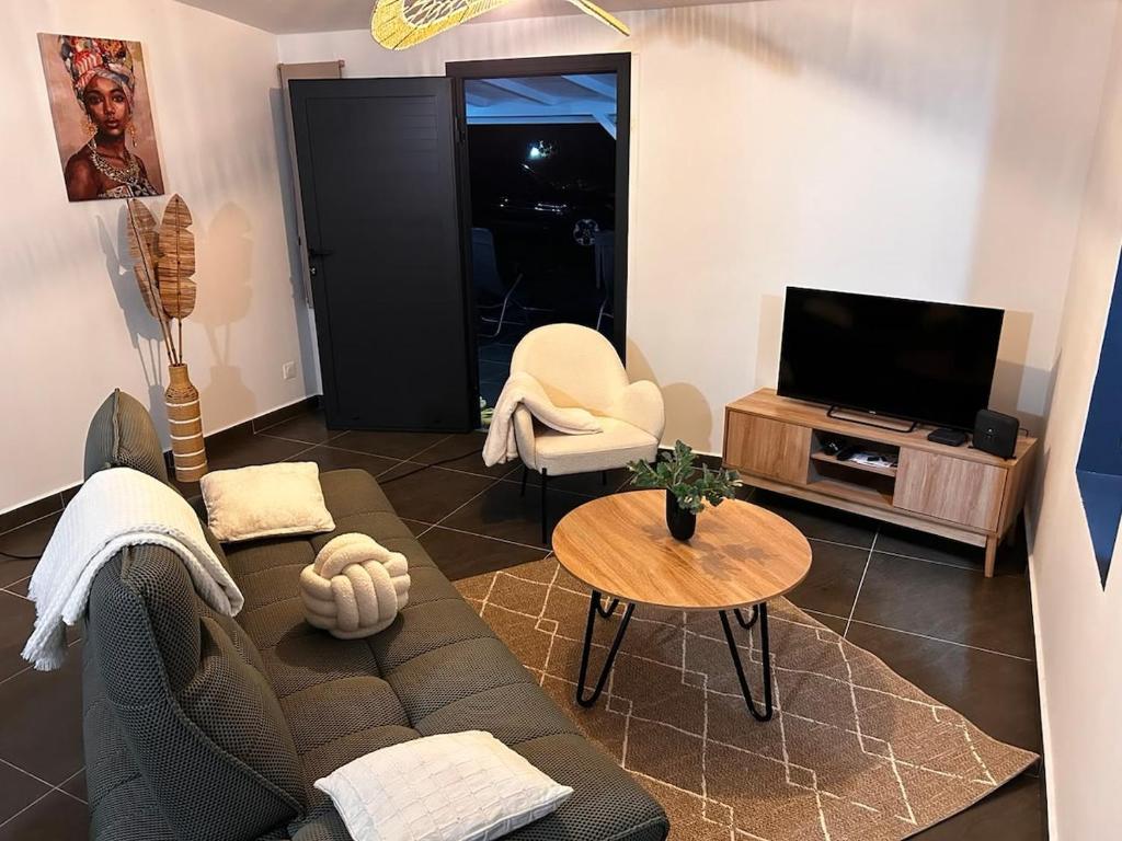a living room with a couch and a tv at Villa Pauline in Les Abymes