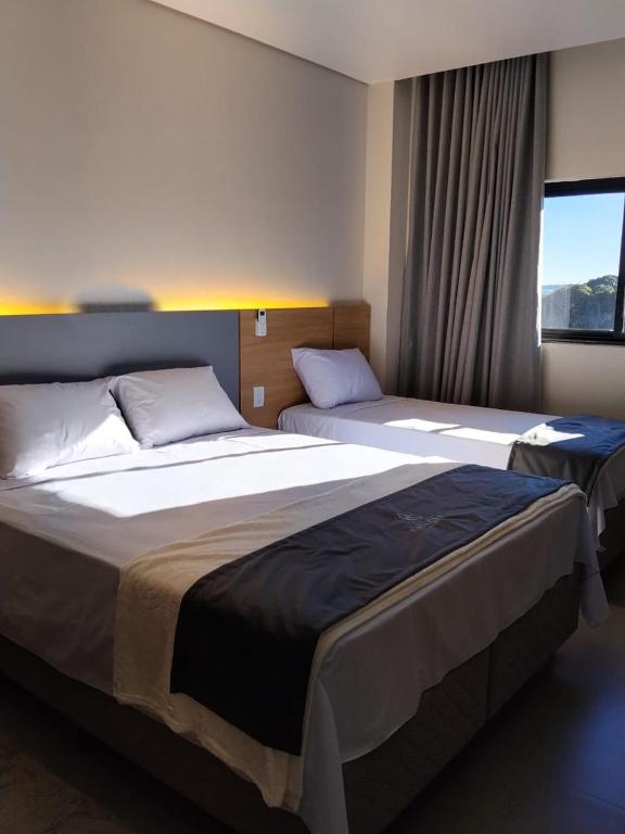 a hotel room with two beds and a window at Hotel do Catarina in Rio Bonito