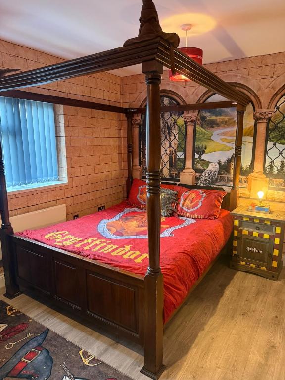 a bedroom with a canopy bed with a red comforter at Harry Potter feature room- Warner bros studios in Watford