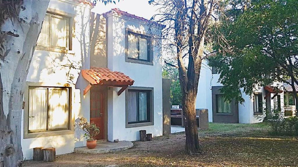 a white house with a door and a tree at Cabañas ConSentidos in Villa General Belgrano