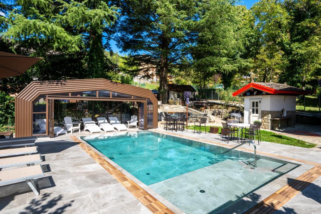 a swimming pool with chairs and a gazebo at Firenze Hotel Suite & Spa in Fanano