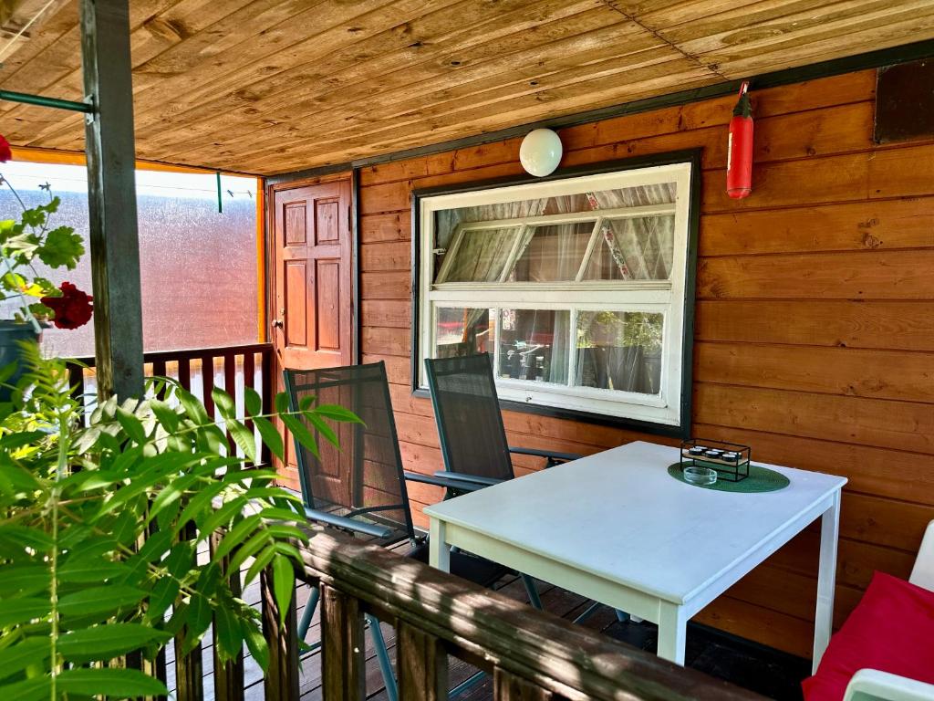 a porch with a white table and a window at Domki ALKANA - domek 3 in Nowęcin