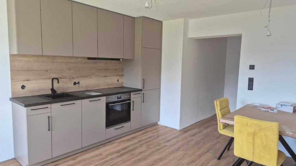 a kitchen with white cabinets and a table and yellow chairs at Hof am Berg in Kaunerberg