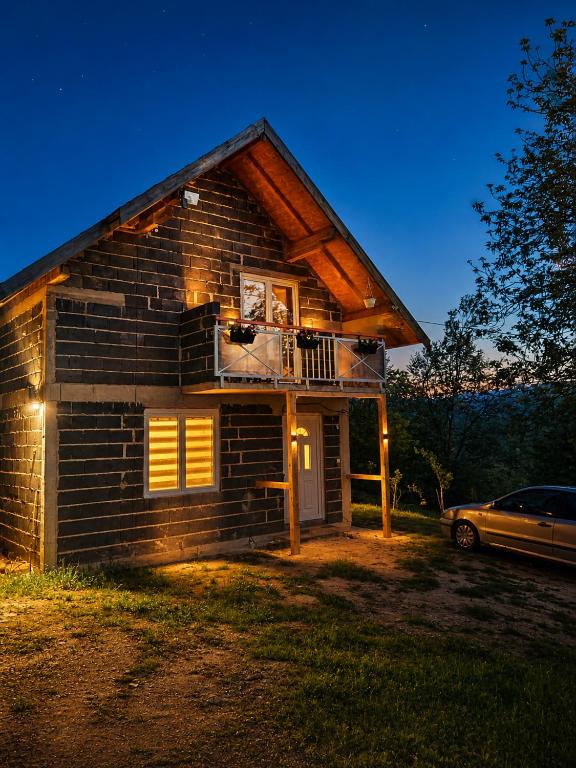 a small log cabin with a balcony and a car at Green Escape in Zavidovići