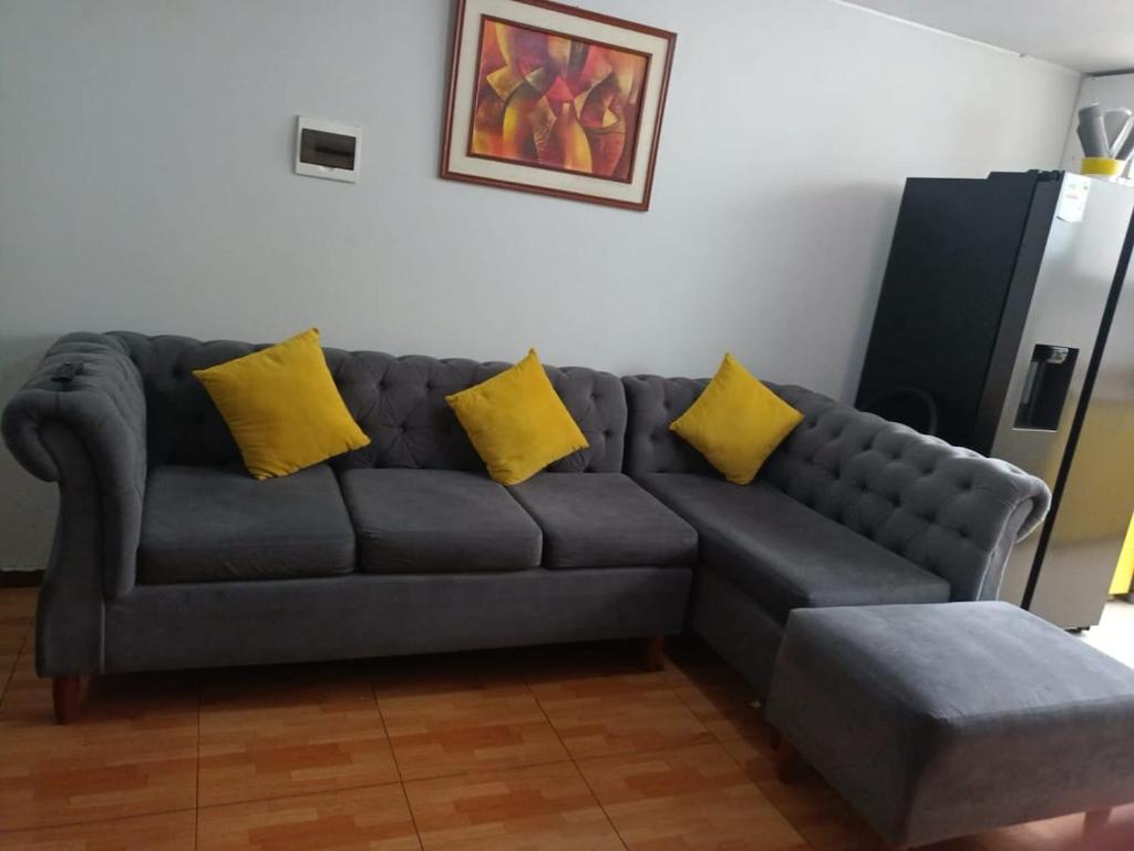a gray couch with yellow pillows in a living room at Yanahuara Urb Ibargüen in Arequipa