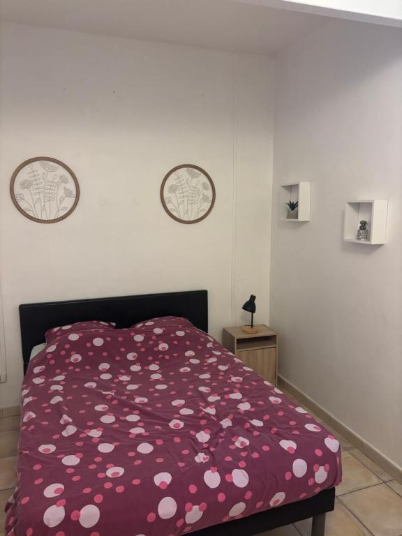 a bedroom with a red comforter with flowers on it at un lit double dans une chambre dans un appartement de 3 chambres en colocation à proximité du centre ville in Toulon