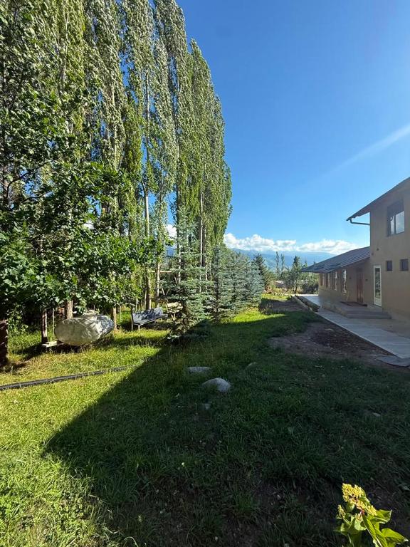 a grassy yard with trees and a building at Kaganat village in Uchar