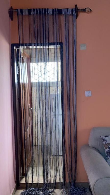 a window with curtains in a room with a couch at Résidence Le Refuge de Mbangue in Kofa