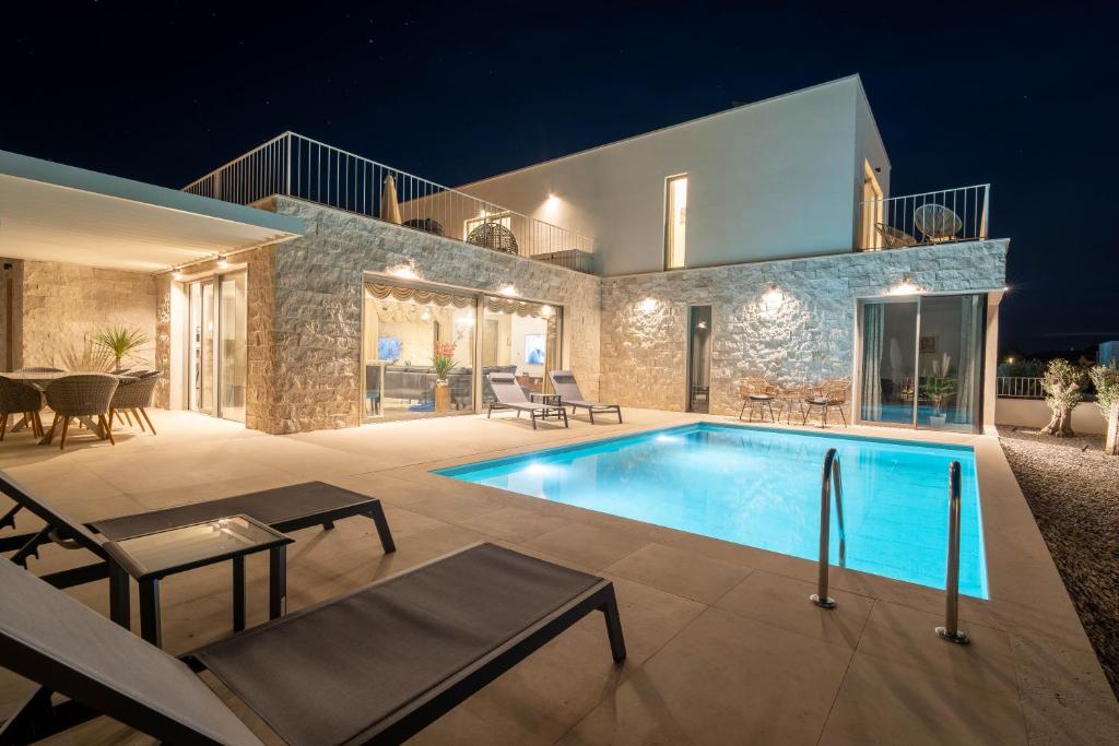 a villa with a swimming pool at night at Villa Oasis mit Meerblick in Supetar