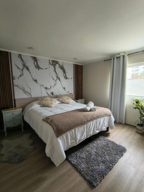 a bedroom with a large bed with a marble wall at Hotel Ágora in Viña del Mar