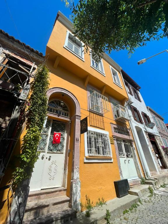 a orange building with a red object in the window at Ayvalık 1892 Konukevi in Ayvalık