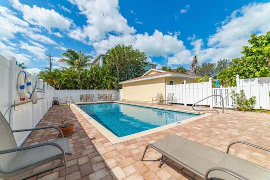 a swimming pool in a backyard with a white fence at Sea Pirate 1 in Holmes Beach