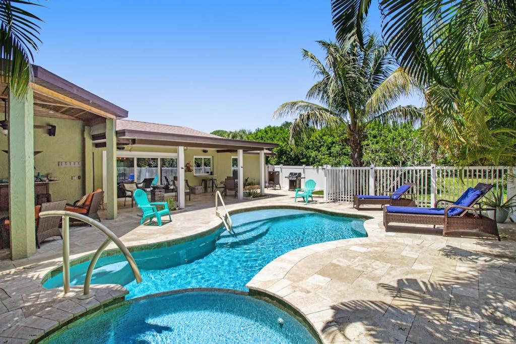 a swimming pool with chairs and a house at Almost There in Bradenton