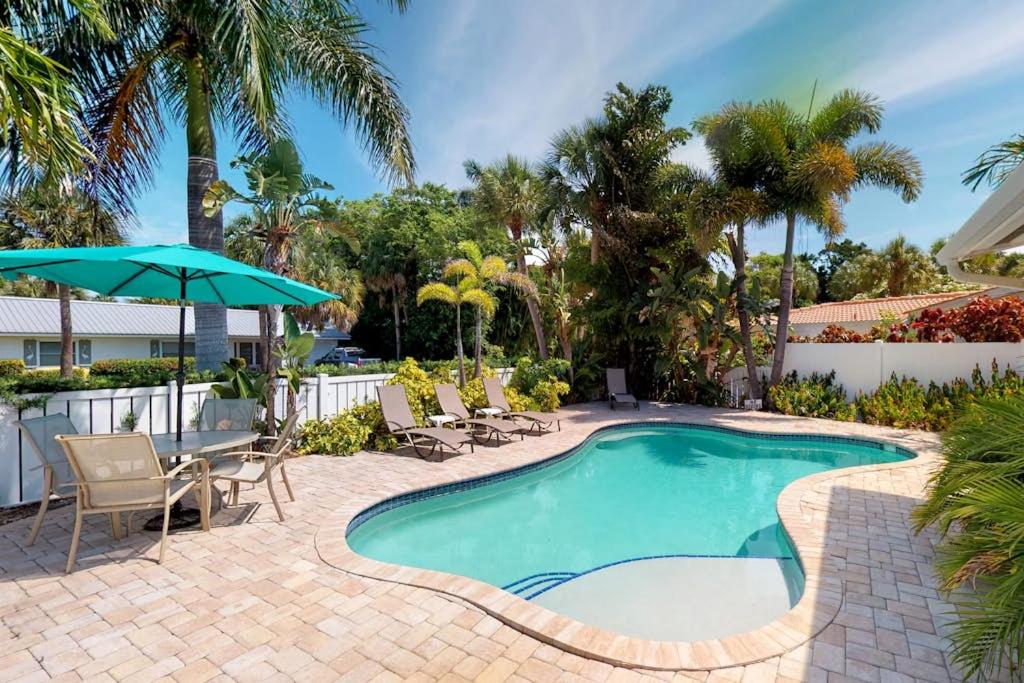 a swimming pool with chairs and an umbrella at Blue Wave Villa East in Anna Maria