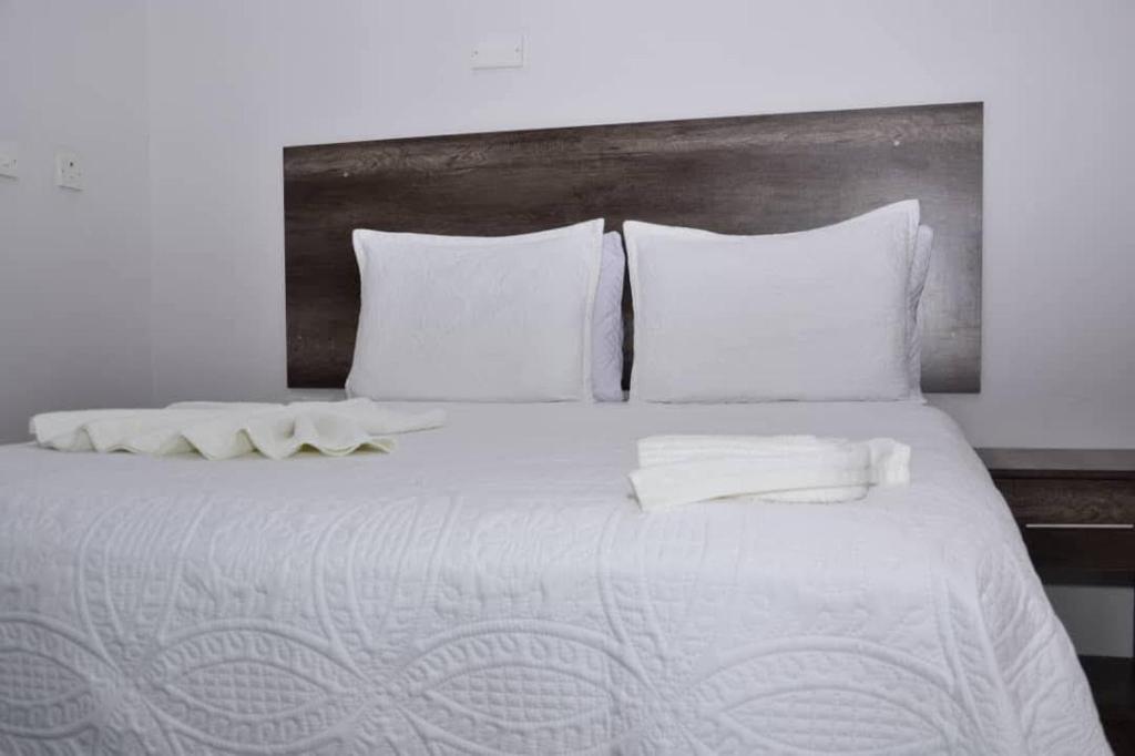 a large white bed with white sheets and pillows at Kgajane Guest House in Molepolole