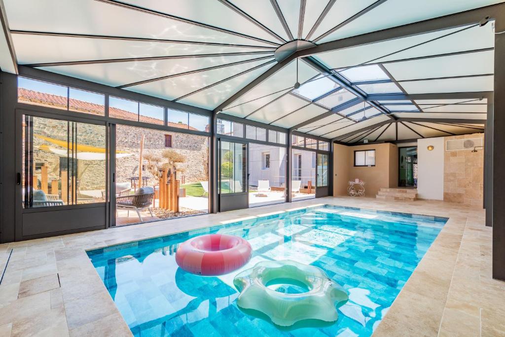 a large indoor pool with a glass ceiling at L'Apothicaire 2 Chambres - Piscine in Montaigu-Vendée