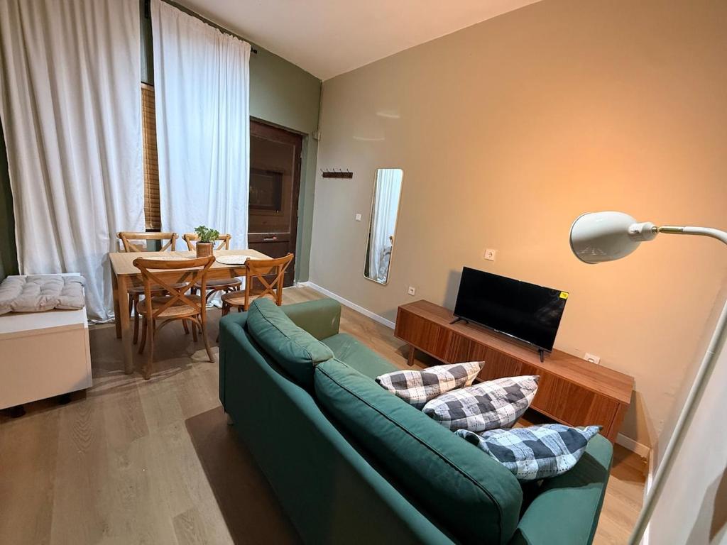 a living room with a green couch and a table at Studio Praia & Sol De Verão in Vila do Conde