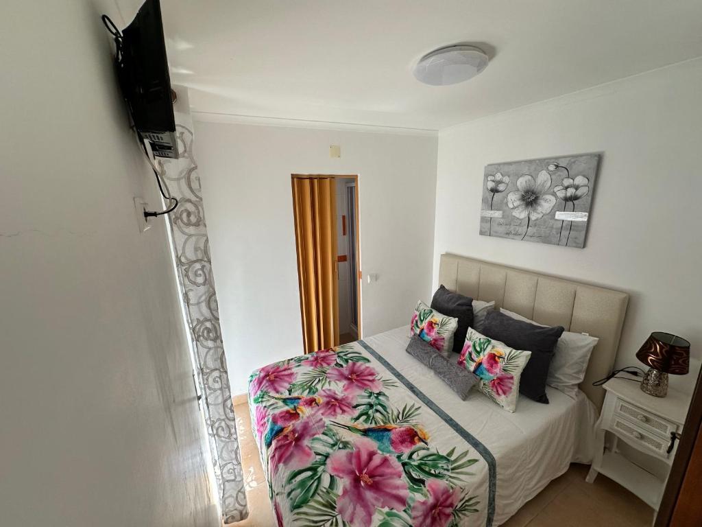 a bedroom with a bed with a floral bedspread at Casa Prédio triplex - Faneca Apartamentos in Nazaré