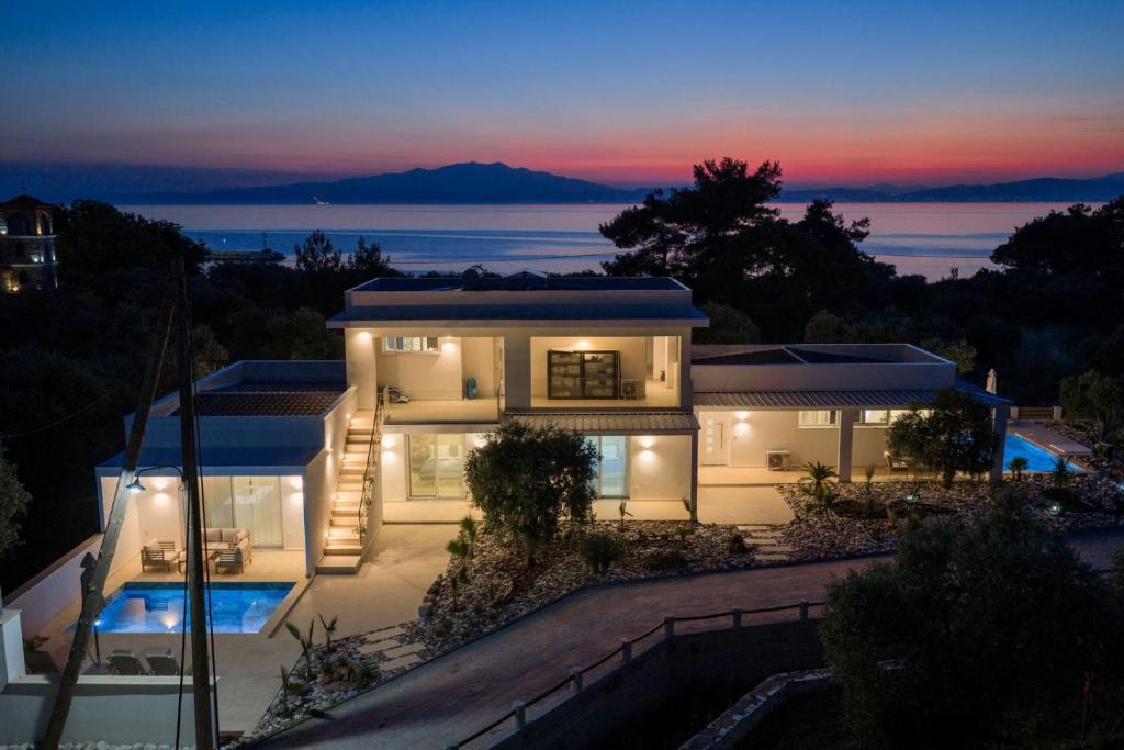 a house with a view of the ocean at night at Oasis deluxe apartments in Skala Rachoniou