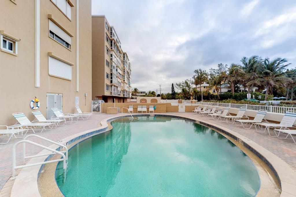 a swimming pool with chairs and a building at Martinique 401S in Holmes Beach